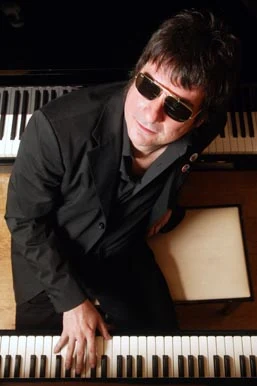 Álvaro Henríquez con anteojos oscuros, inclinado sobre un piano de cola