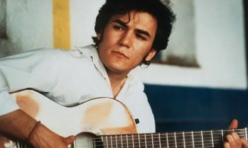 Retrato de Ismael Serrano con una guitarra al hombro