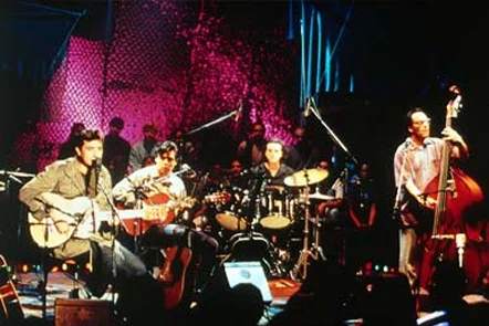 Fotografía de una banda tocando en vivo con guitarras acústicas, batería y contrabajo